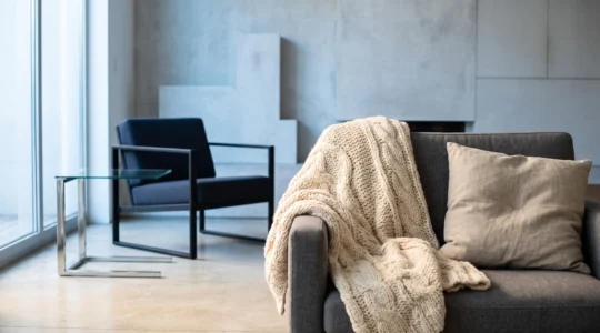 Contraste entre un salon de diseño frio y aséptico y un rincón cálido creado con textiles naturales