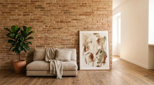 Pared de ladrillo original restaurada en un salón luminoso con mobiliario contemporáneo y textiles cálidos